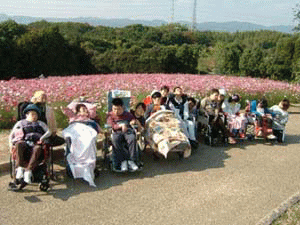 写真：花畑の前にならぶ車いすに乗った人たち