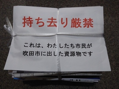 写真：新聞紙の束に載せた意思表示用紙