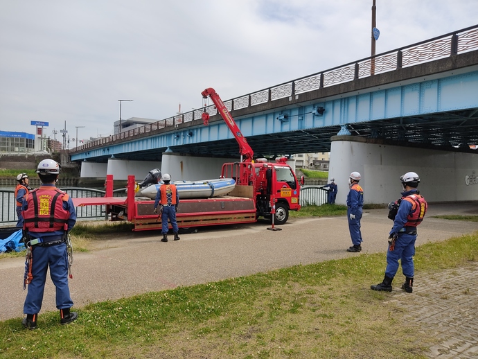 クレーンを用いてボートを神崎川に搬送中