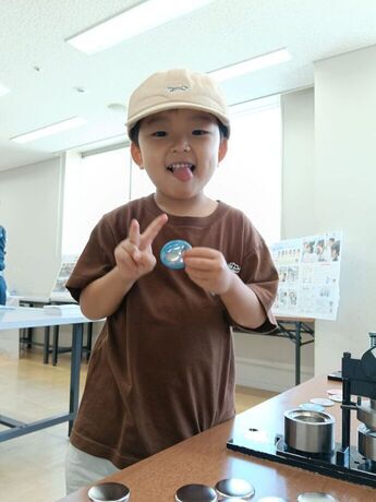 缶マグネット作りをしてピースする男の子